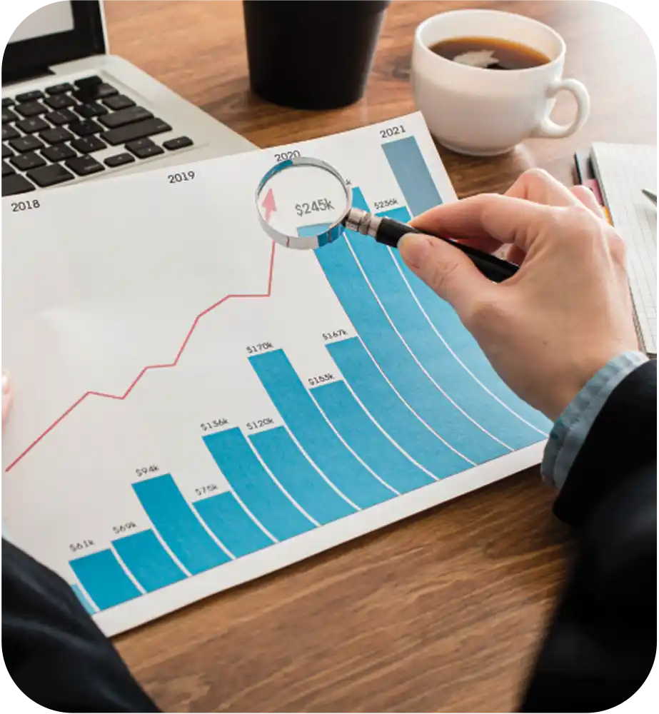 Business professional reviewing a financial growth chart with a magnifying glass to analyze revenue performance trends.