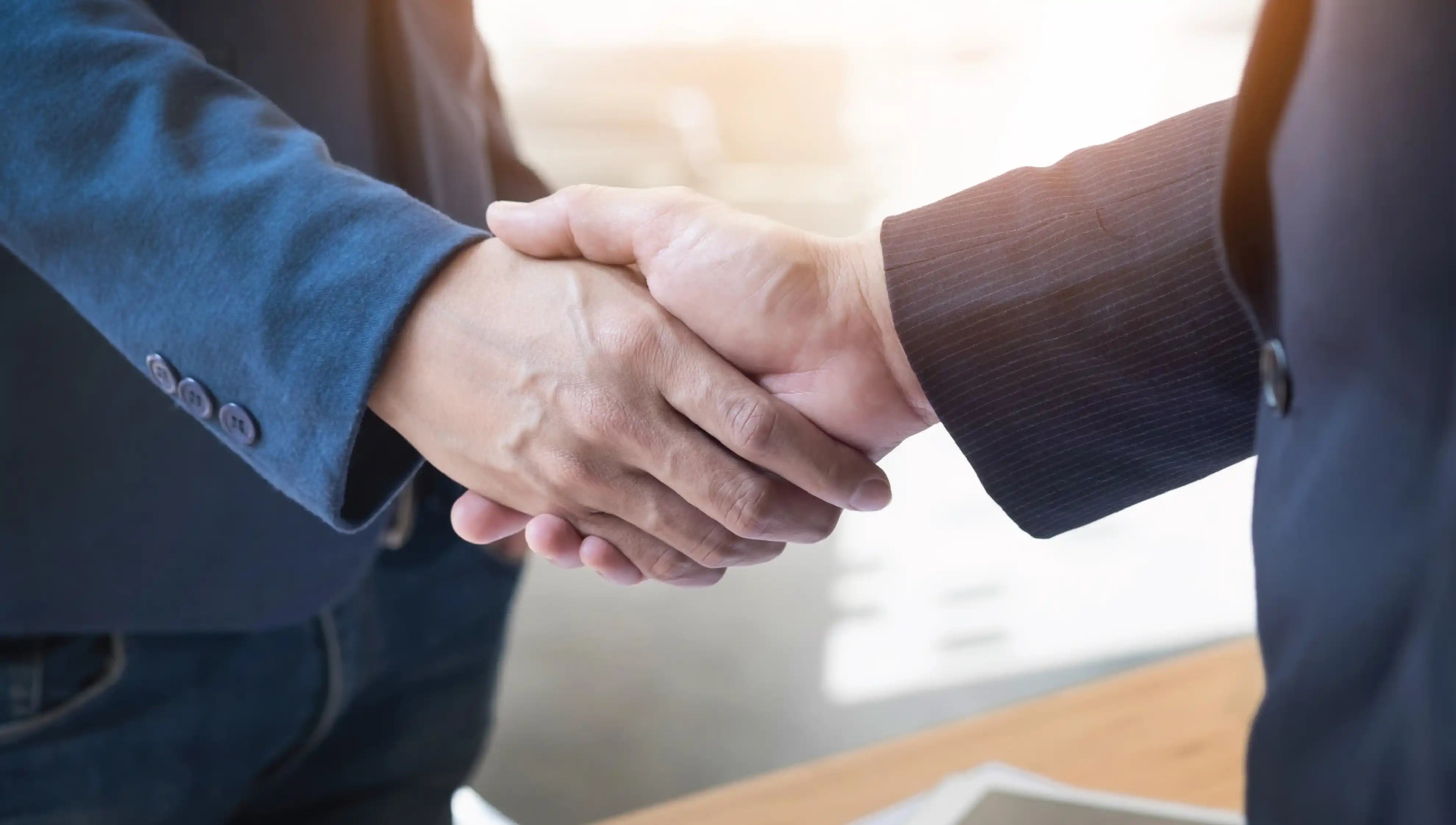 Two business professionals shaking hands to represent a successful partnership or agreement.