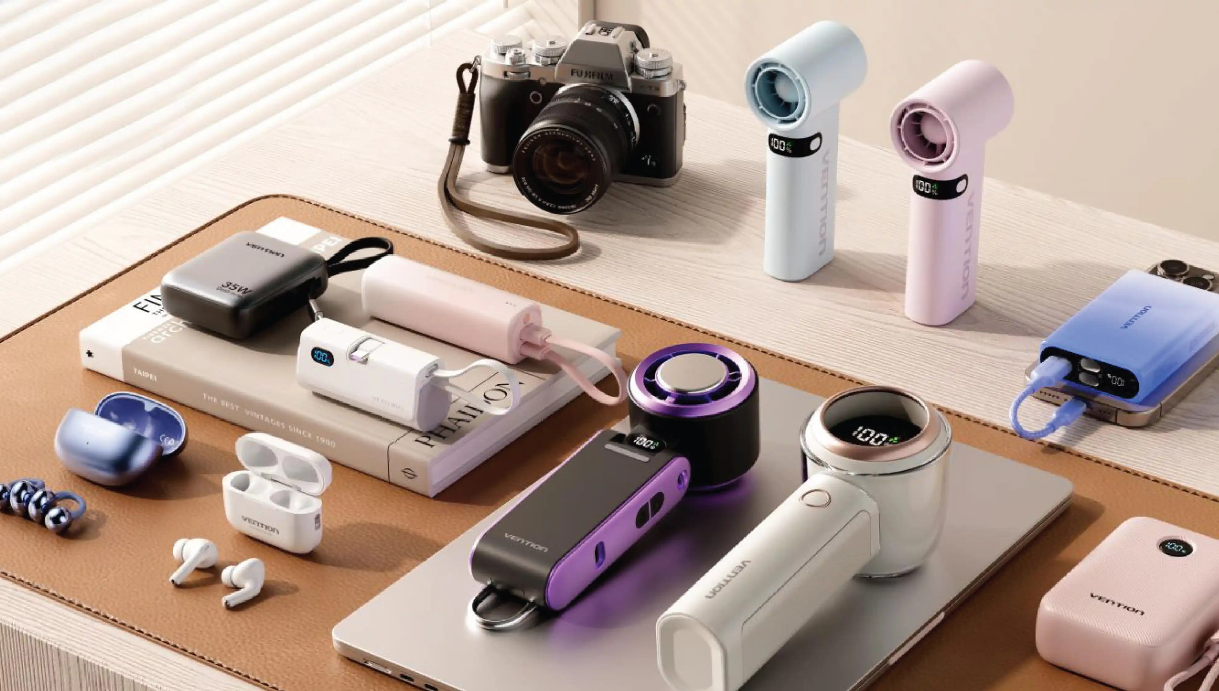 Modern tech accessories including chargers, earbuds, camera, and portable gadgets arranged on a minimalist work desk.