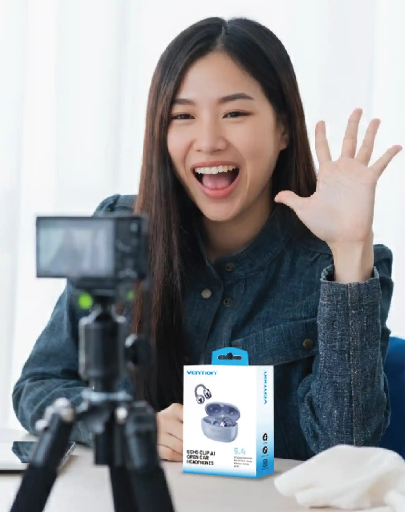 Content creator recording a product review video showcasing wireless earbuds and accessories on a desk setup.